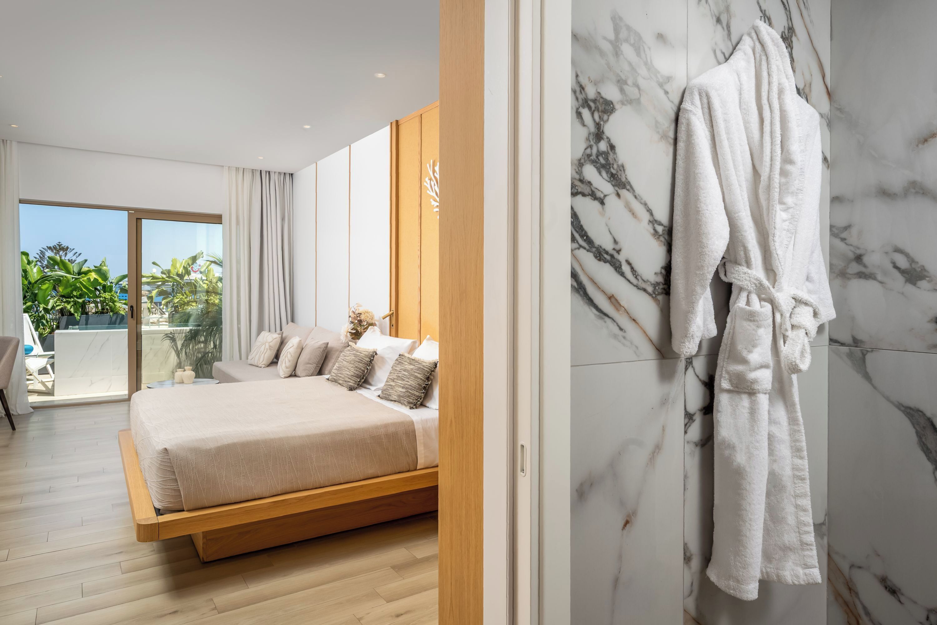Une chambre moderne avec un grand lit, un plancher en bois, un mur en marbre et un balcon agrémenté de plantes.