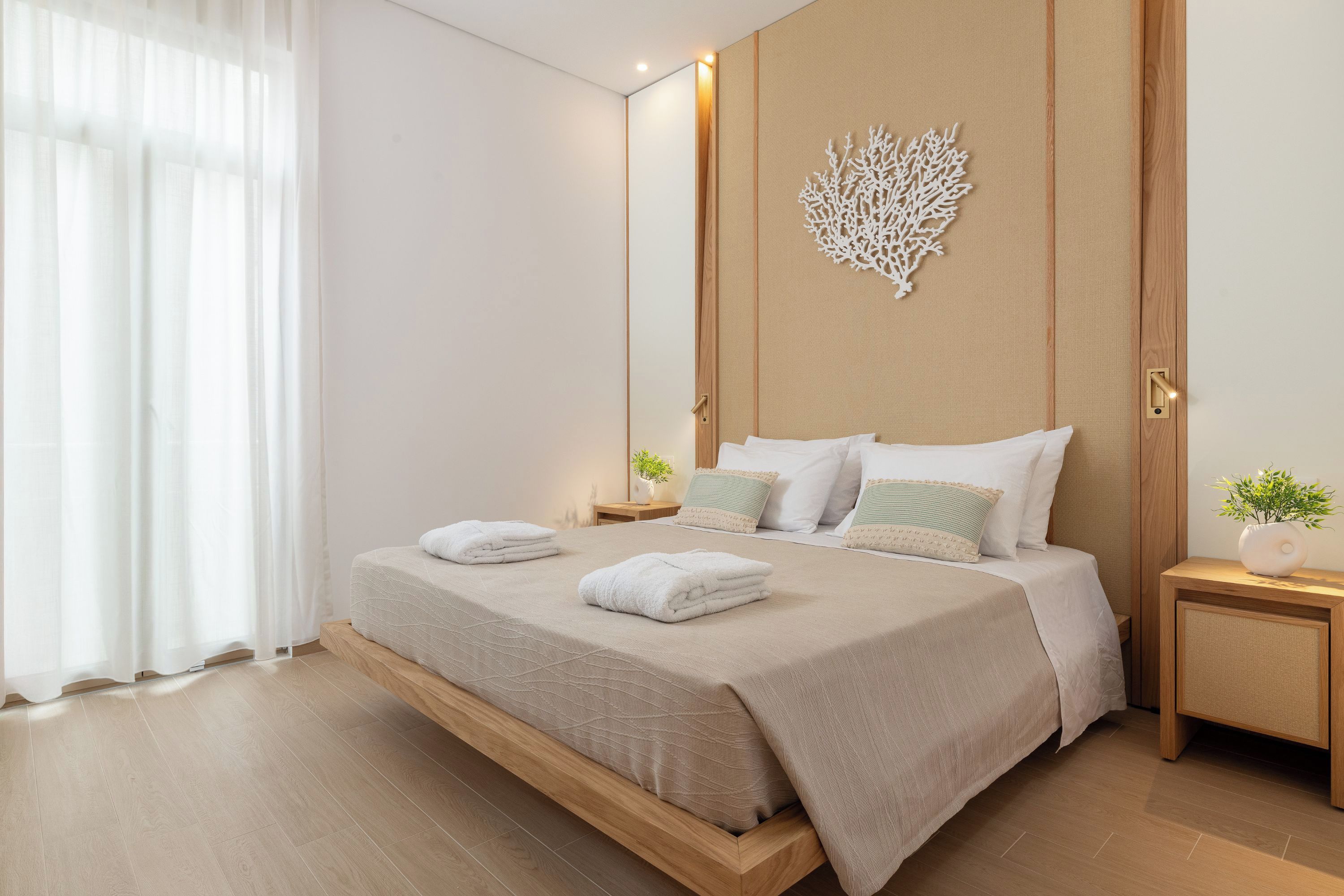 A modern bedroom with a bed, nightstands, a wall-mounted decor piece, and a window with curtains.