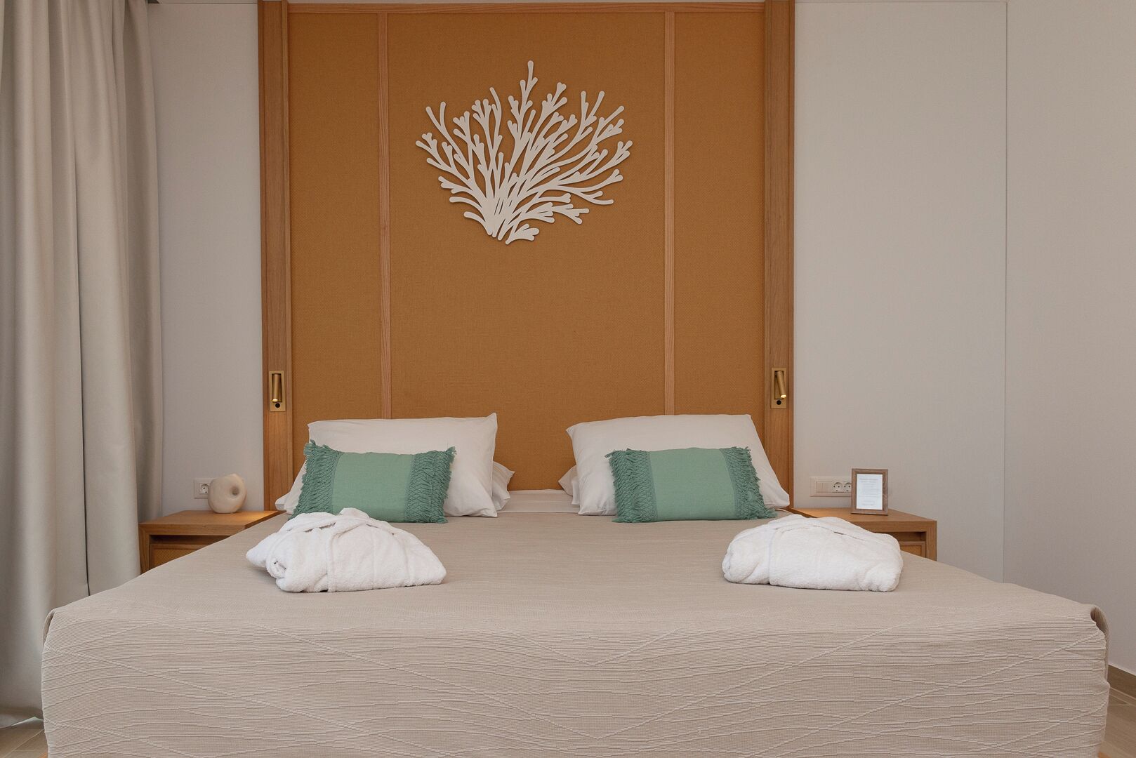 A neatly made bed with two pillows, a decorative wall piece, and a nightstand with a lamp.