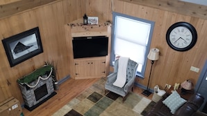 Ein gemütliches Wohnzimmer mit Kamin, Ledersofa und einem großen Fenster.