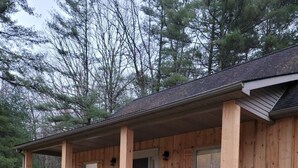 Eine Holzhütte mit überdachter Veranda, Sitzgelegenheiten im Freien und einer Treppe zum Eingang.