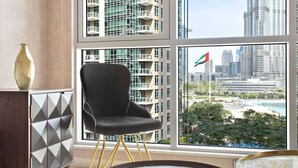 Een moderne kamer met een groot raam, een zwarte stoel en een decor kast.