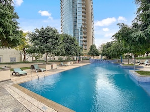 A swimming pool with lounge chairs and a tall building in the background.