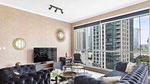 Een moderne woonkamer met een grote televisie, comfortabele zithoek en uitzicht op hoge gebouwen.