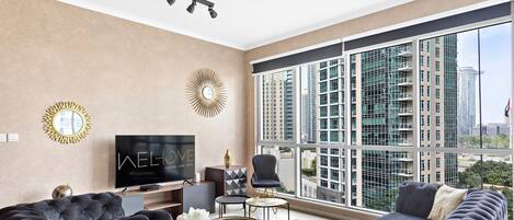 A modern living room with a large TV, comfortable seating, and a view of high-rise buildings.