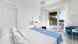 Habitació d'hotel amb un llit gran, un balcó amb vistes, una taula de treball i una cadira.