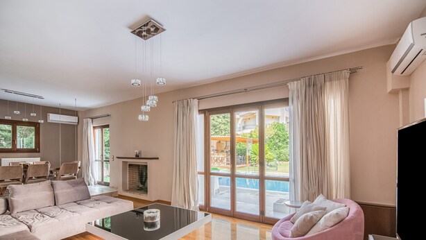 A spacious living room with a large sofa, a pink bean bag, a coffee table, and a fireplace. - Inviting Villa in Anavissos With Communal Pool (Saronikos)