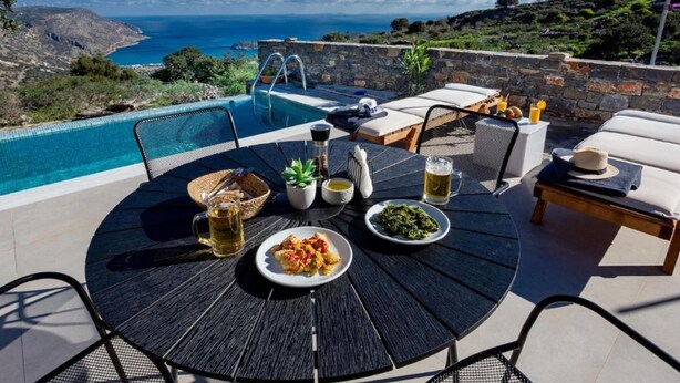 An outdoor dining area with a pool, overlooking a scenic view of the sea and hills. - Mesmerising Villa in Plaka Elounda With Pool (Agios Nikolaos)