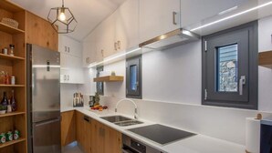 A modern kitchen with stainless steel appliances, wooden cabinets, and a large island with a built-in stove. - Mesmerising Villa in Plaka Elounda With Pool (Agios Nikolaos)