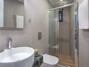 A modern bathroom with a glass shower enclosure, a white sink, and a marble countertop.