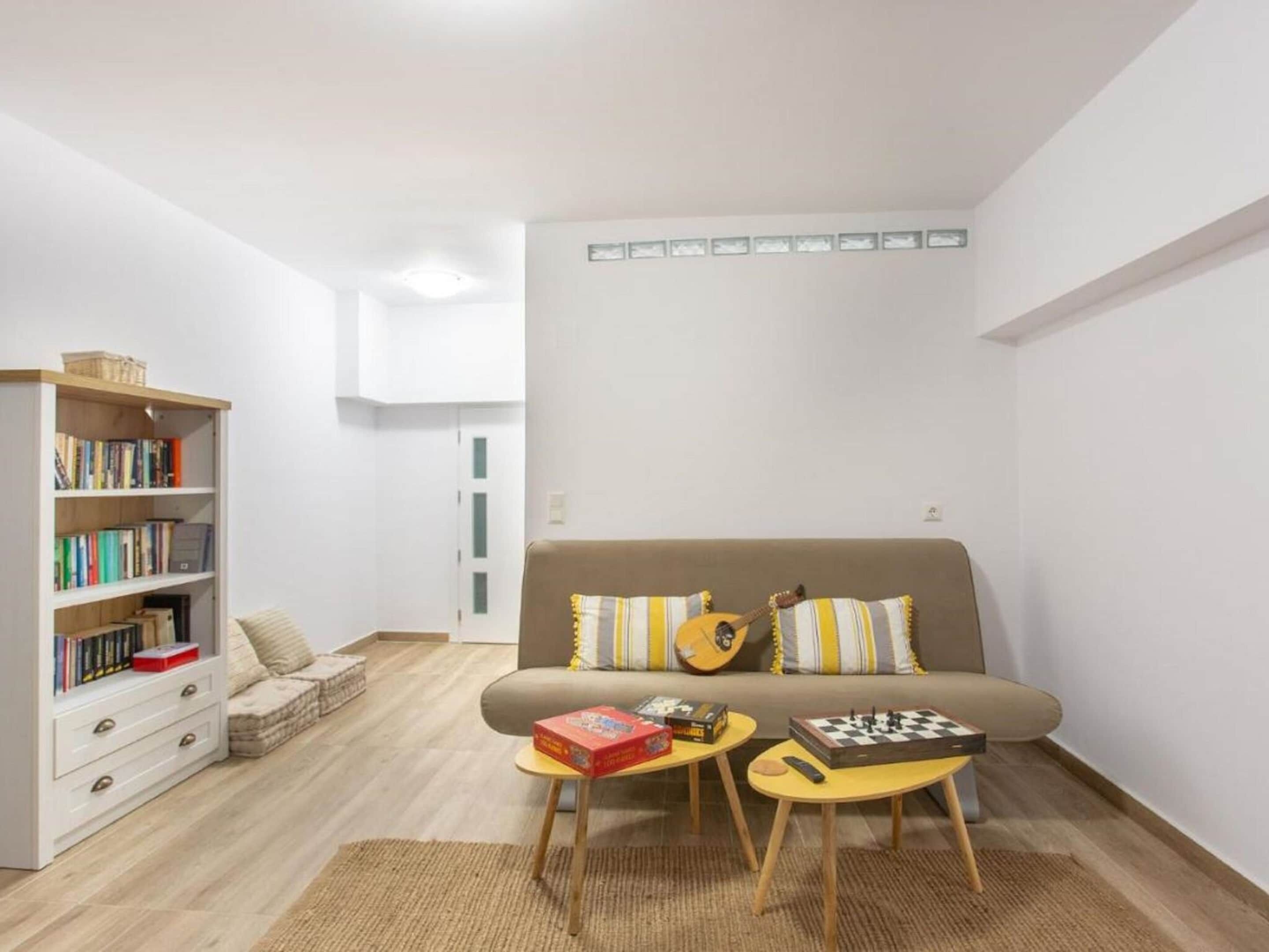 A living room with a sofa, a bookshelf, and two small tables with board games.
