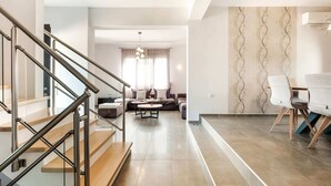 A modern living room with a staircase, a sofa set, and a dining area with chairs. - Villa in Crete With Stunning Views & Privacy (Rethymno)
