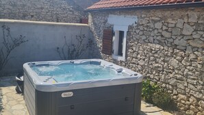 A hot tub in a stone-walled outdoor area with a tiled roof. - Home With Swimming Pool & Outdoor Kitchen (Nin)