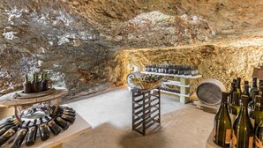 An underground wine cellar with stone walls, wine racks, and a variety of wine bottles. - 737 Trulli con Piscina ad Ostuni (Ostuni)