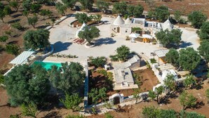 An aerial view of a property with multiple buildings, a swimming pool, and surrounding trees. - 737 Trulli con Piscina ad Ostuni (Ostuni)