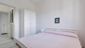 Une chambre à coucher avec un lit, une armoire, une table de chevet et un tableau encadré au mur.