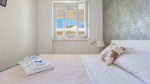 A hotel room with a bed, a window with a view of a pool, and a textured wall.