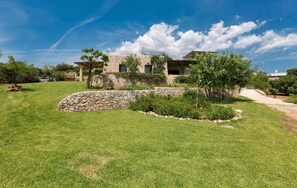 Una casa in pietra con un muro di pietra e un prato.