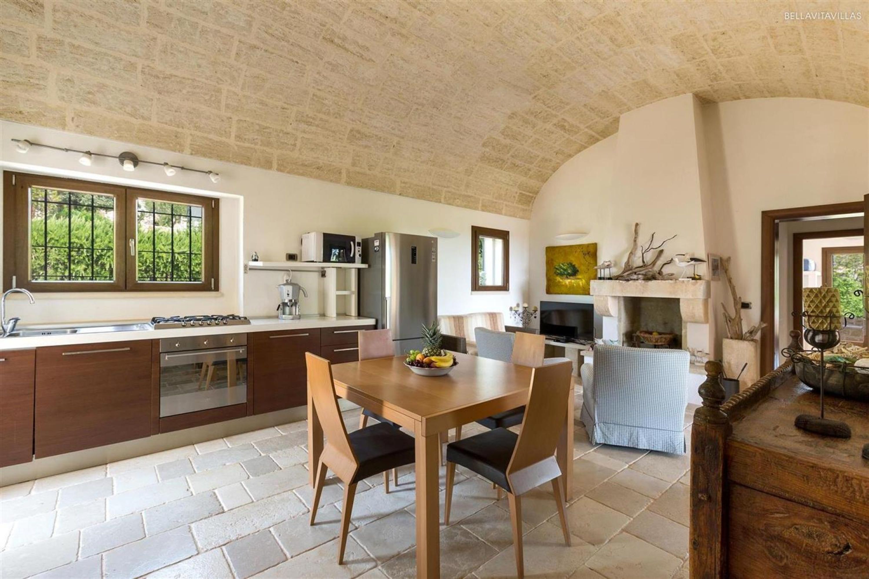 A kitchen with a dining table, chairs, a refrigerator, and a stove.