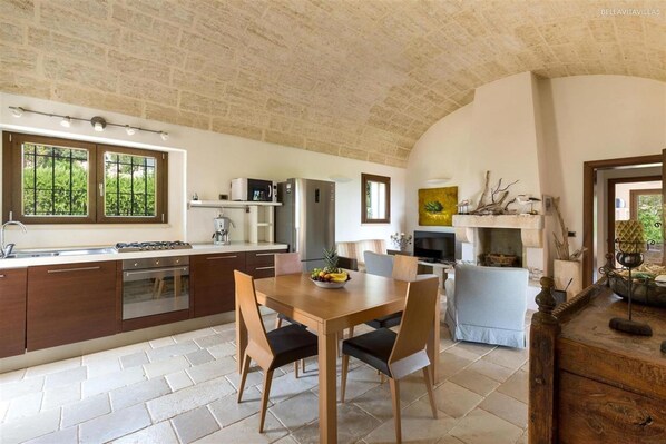 Une cuisine équipée d’une table à manger, de chaises, d’un réfrigérateur et d’une cuisinière.