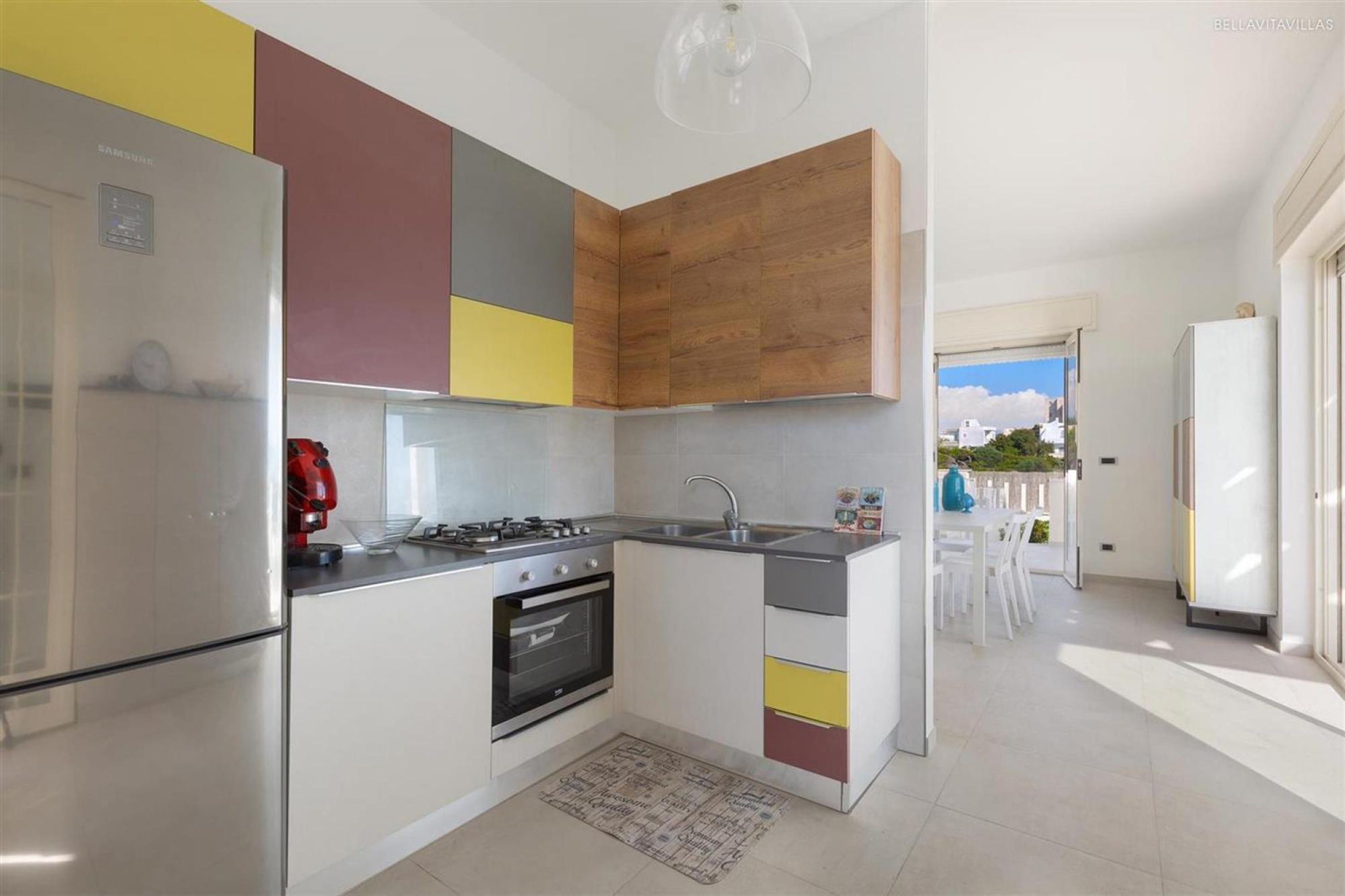 Una cocina moderna con horno empotrado, estufa a gas y refrigerador de acero inoxidable.