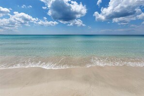 A beach with clear turquoise water and a sandy shore under a partly cloudy sky. - 1826 Villetta Solaire (Porto Cesareo)