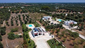 Vue aérienne d’un quartier résidentiel avec plusieurs maisons, une piscine et un panneau solaire installé sur l’un des bâtiments.