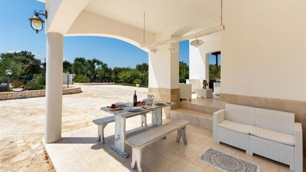 Une terrasse extérieure avec une table dressée pour le repas, un canapé et une lampe.