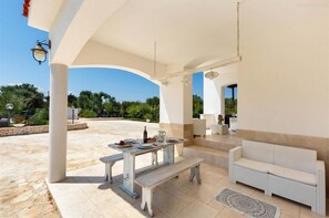Eine Terrasse im Freien mit Esstisch, einer Couch und einer Lampe.