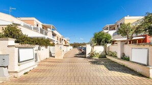 A residential street with houses on both sides, paved with bricks, and a clear blue sky. - 2206 Perla del Boncore (Nardò)