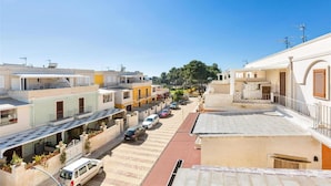 A residential street with colorful houses, a clear sky, and parked cars. - 2206 Perla del Boncore (Nardò)