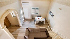 Ein geräumiger Wohnbereich mit einer großen Couch, einem Esstisch mit Stühlen und einer Treppe.