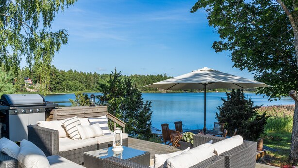 Une terrasse extérieure avec des meubles en osier, un barbecue et une vue sur un lac.