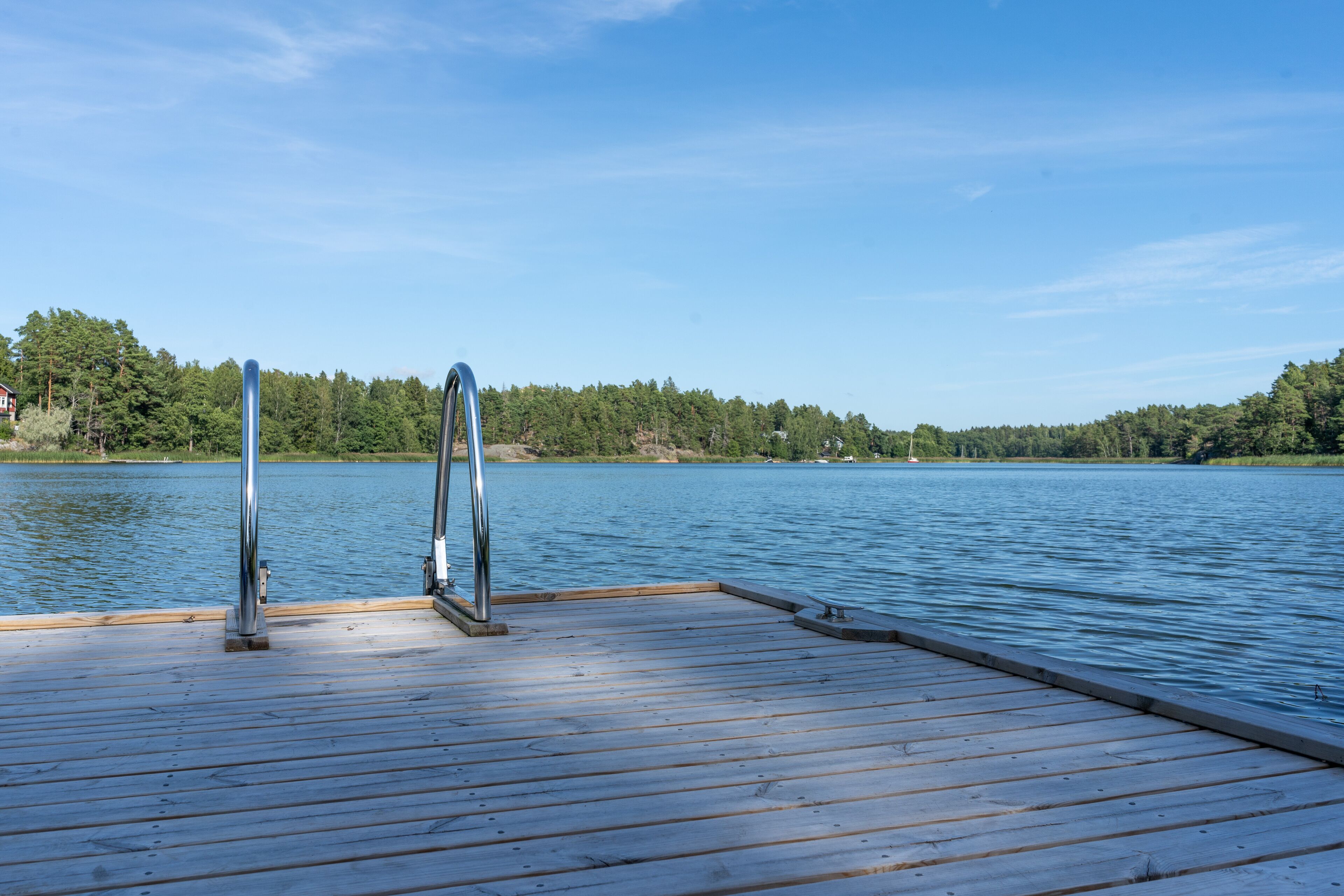 Un muelle de madera que se adentra en un lago tranquilo bajo un cielo despejado.
