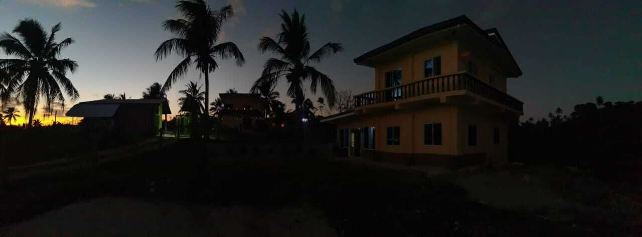 A two-story building with a balcony, surrounded by palm trees.