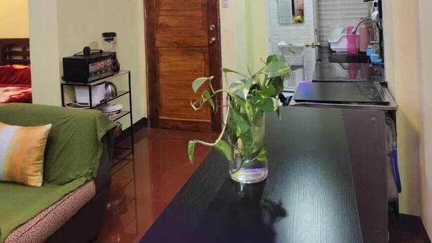 Un espacio habitable compacto con sofá, mesa de comedor, zona de cocina con armarios y puerta de madera.