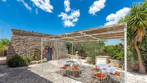 A stone building with a covered patio area featuring a table and chairs. - 373 Villa con Piscina a Casarano Gallipoli (Casarano)