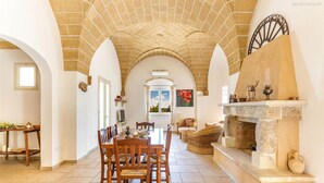 A dining area with a brick ceiling, a fireplace, and a view through an archway. - 373 Villa con Piscina a Casarano Gallipoli (Casarano)