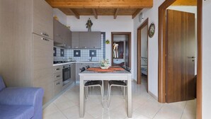 A compact kitchen with modern appliances, a dining table with chairs, and a wooden ceiling. - 995 Trilo Corallo in Porto Cesareo (Porto Cesareo)