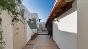 A narrow, tiled courtyard with a staircase leading to an upper level, surrounded by white walls and potted plants. - 995 Trilo Corallo in Porto Cesareo (Porto Cesareo)