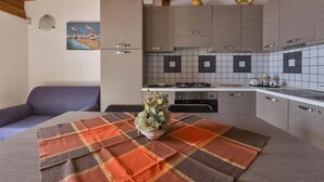 A modern kitchen with grey cabinets, a tiled backsplash, and a dining area with a plaid tablecloth. - 995 Trilo Corallo in Porto Cesareo (Porto Cesareo)