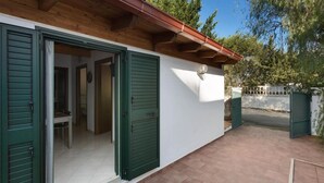 A building with green shutters, a tiled patio, and a wooden roof. - 995 Trilo Corallo in Porto Cesareo (Porto Cesareo)