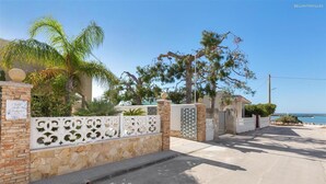 A gated property with stone walls, decorative metal gates, and a view of the sea. - 1183 Villino Delle Orchidee Est (Nardò)