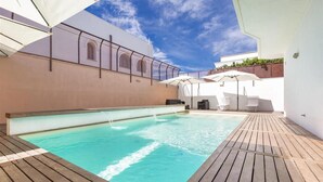 A pool area with a wooden deck, white umbrellas, and a white building with arched windows. - 1786 B B Joy Home - Camera 2 (Maruggio)