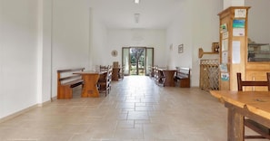 A spacious hallway with wooden benches and tables, leading to a door at the end. - 1863 Agriturismo Podere San Giorgio - Camera Matrimoniale by Barbarhouse (Otranto)