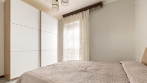 Ein Schlafzimmer mit einem Bett, einem Kleiderschrank und einem Fenster mit Vorhängen.