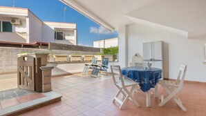 Eine Außenpatio mit Tisch und Stühlen, einem Tor und einem Gebäude im Hintergrund.