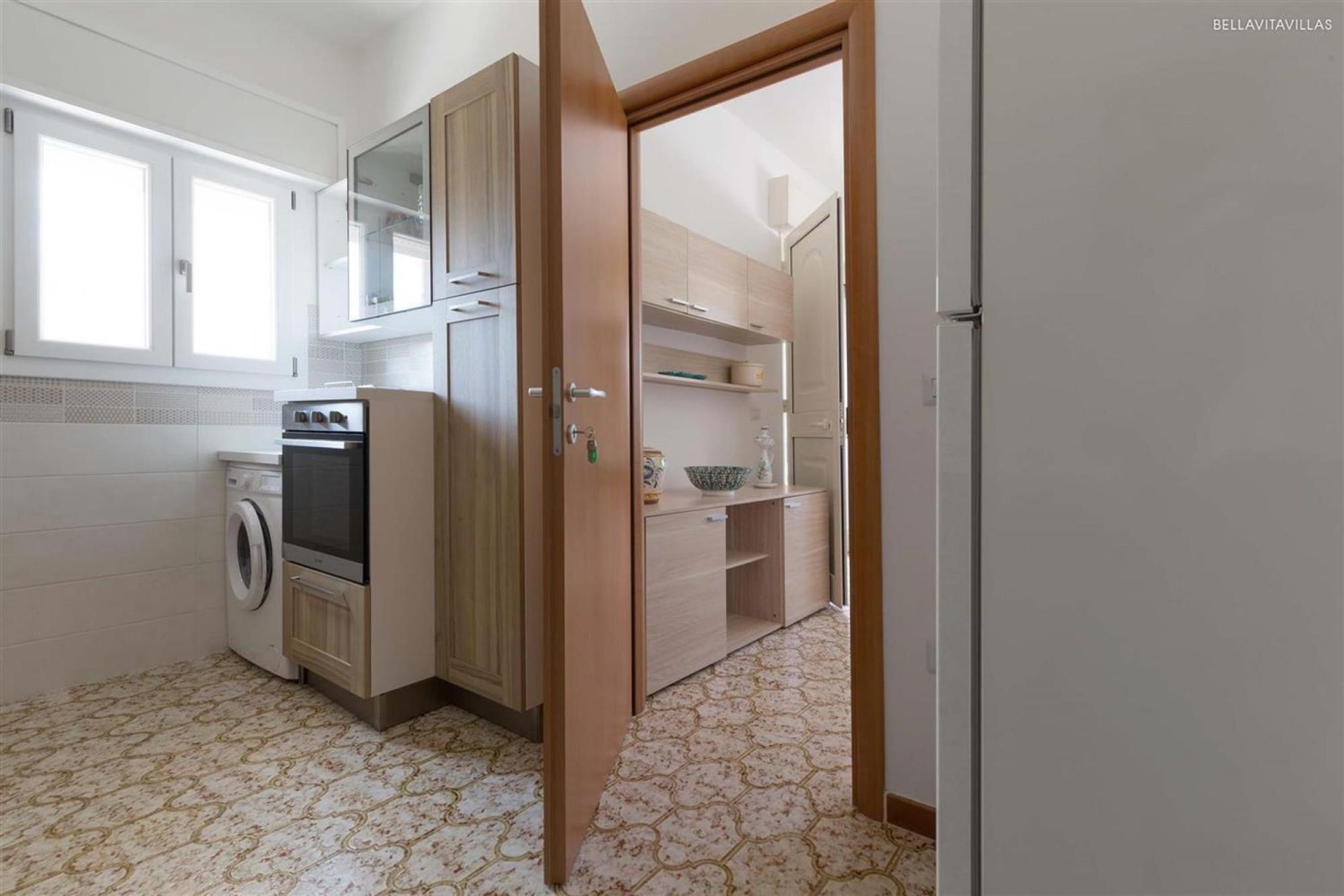 A kitchen with a washing machine, oven, and wooden cabinets.
