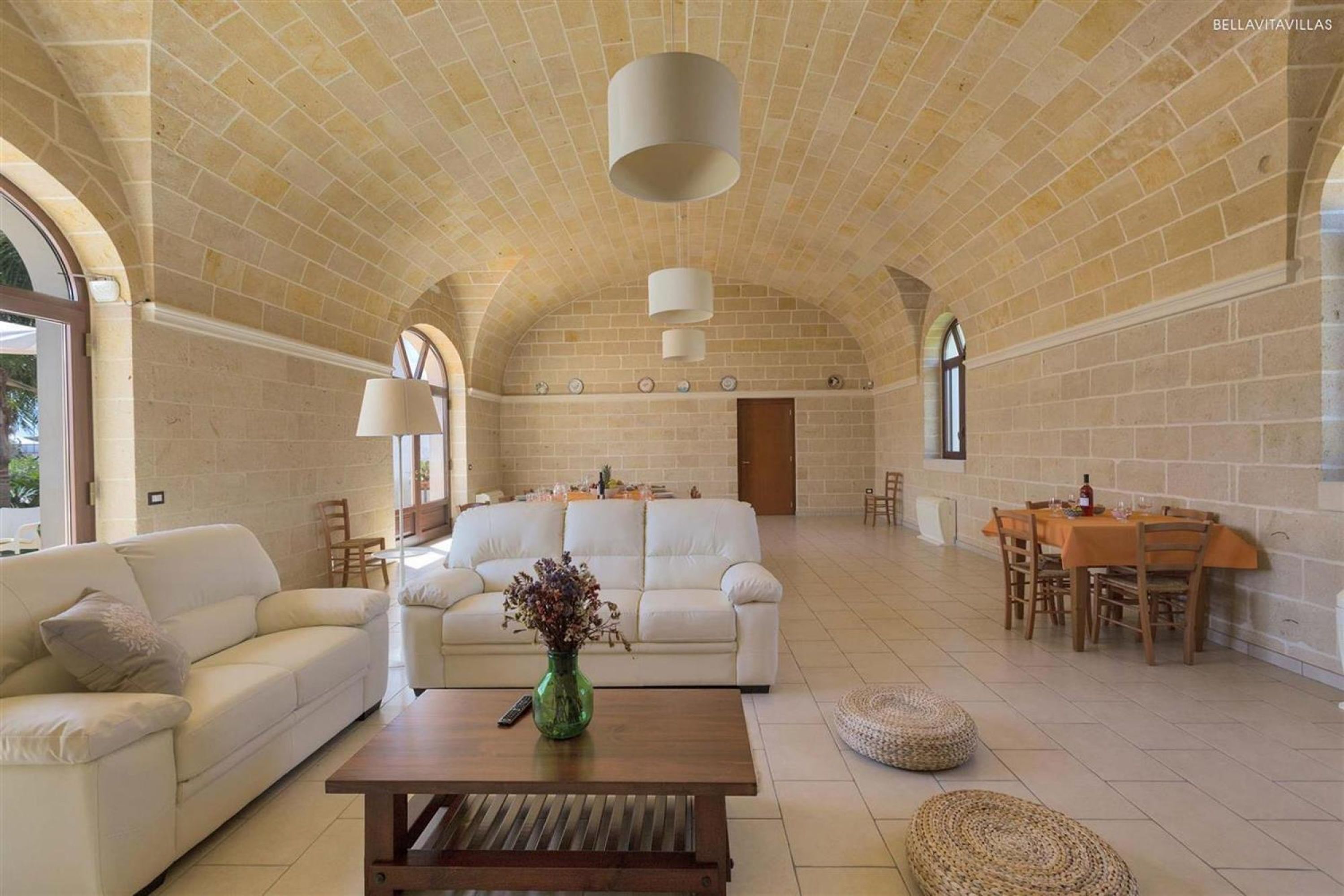 A spacious living area with a white sofa, a coffee table, and a dining table with chairs.