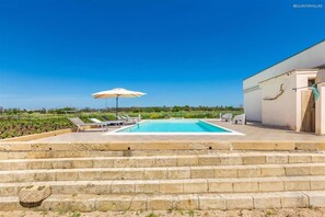 A swimming pool with steps leading up to it, surrounded by lounge chairs and an umbrella. - 2340 Villa Il Neto by Perle di Puglia (Casarano)